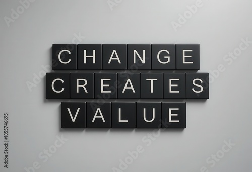 Change Creates Value Inspirational Quote on Black Tiles Against Gray Wall