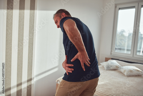 Tableau sur toile Man with hip, back, spine and sciatica pain at home.
