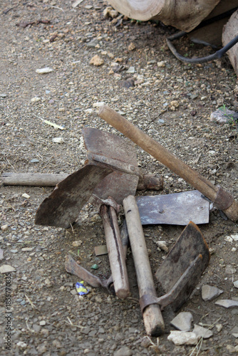 Old Rusty Farming Hand Tools on Ground with Wooden Handles