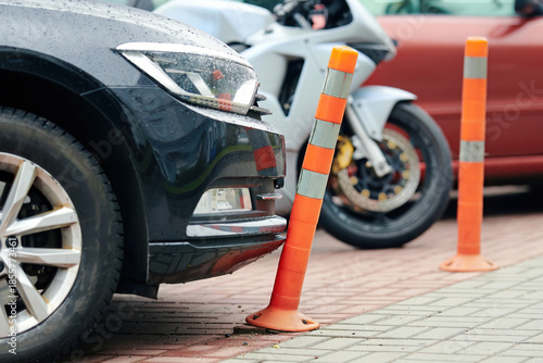 Fotografia Car bumper touching flexible plastic bollard on parking lot, minor contact, damage to reflective warning post, everyday parking incidents and traffic safety infrastructure