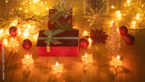 Red gift box and candlelight on a wooden table.