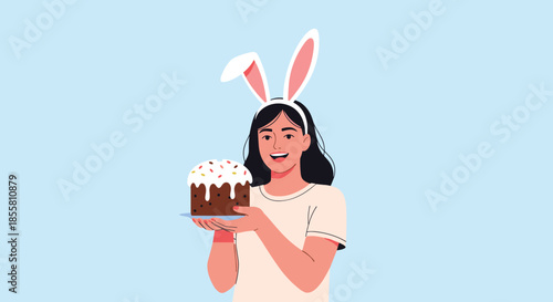 Happy young woman wearing bunny ears smiling and holding a traditional decorated Easter cake to celebrate the spring holiday.