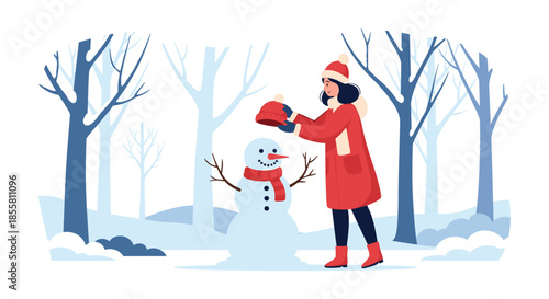 Young woman in a red winter coat and hat is building a snowman in a snowy forest on a beautiful cold winter day.
