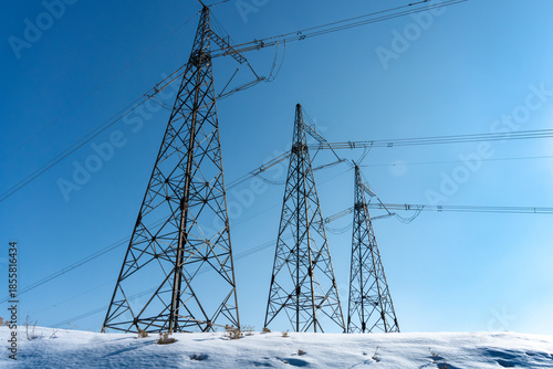 Fotografi Low angle view of high voltage transmission towers under clear blue sky in winter