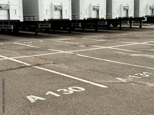 Cargo Transport Yard Under Cloudy Sky Scene, Efficient Logistics Area With Neatly Aligned Trailers, Minimalist Industrial Setting Showing Uniform Rows Of Cargo Trailers On Asphalt