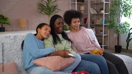 African american mother watching television with two daughters