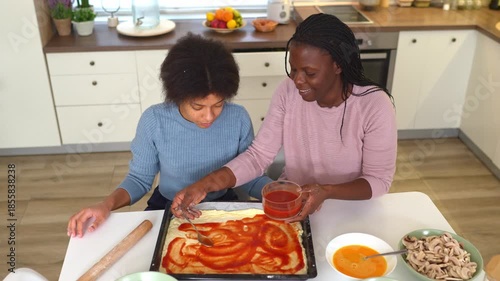 African american mother and daughter preparing pizza at home
