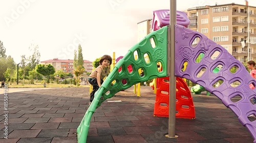 Kid playing on a playground in a park. Suddenly, The child excitedly chants in Arabic, “Raise your head high, you are a free Syrian” expressing joy, pride, freedom and identity while growing up abroad