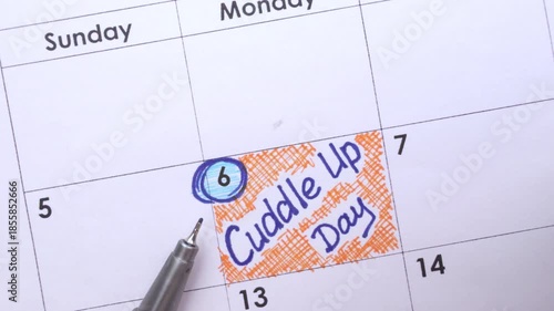 Paper calendar with handwritten reminder Cuddle Up Day on it with pen. January 06.