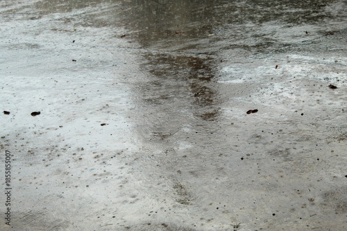 raindrops falling on a wet concrete surface during cloudy weather