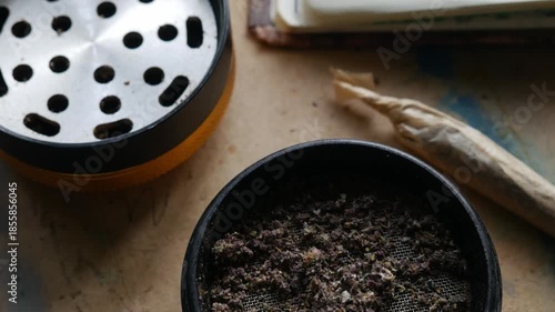 Herb Grinder with Ground Cannabis and Pre-rolled Joint on Table