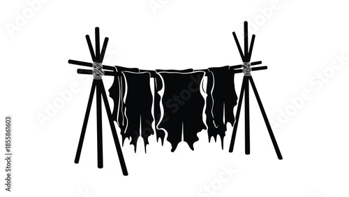 Silhouette of animal hides drying on a line between two wooden stands outdoor isolated on white background