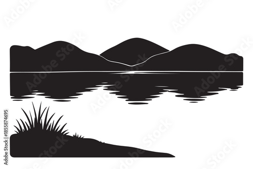 Peaceful silhouette of mountains reflecting in a calm lake with grass on the shore