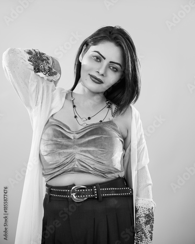 Black and white fashion portrait of a confident woman posing with her hand behind her head against a clean studio background. Monochrome studio photography expressing timeless elegance, femininity, se