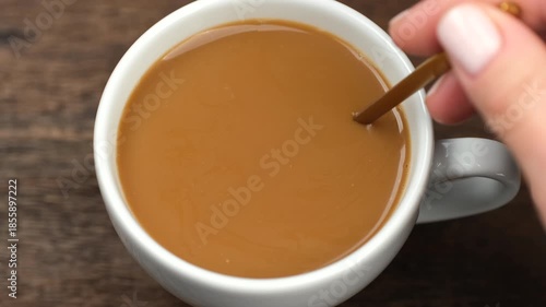 Coffee with milk. Female hand stir coffee with milk, close up