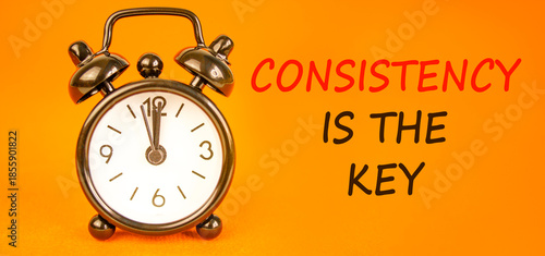 Consistency is the key symbol. Concept words Consistency is the key on beautiful orange paper. Beautiful orange paper background. Black alarm clock. Business consistency is the key concept. Copy space