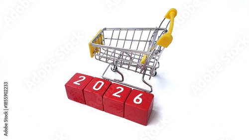 A small metal shopping cart with yellow handles is positioned on top of red blocks displaying the numbers 