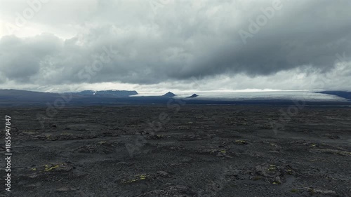 Dark Volcanic Terrain and Melting Glacier in Distance