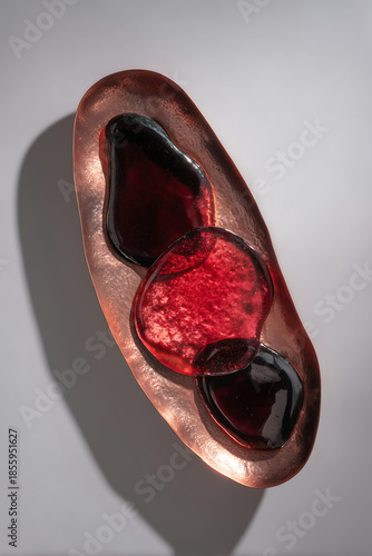 A copper plate is shaped into a simple vessel form, holding abstract, flowing pools of transparent and opaque enamel in volcanic red and black. The piece is about the essence of the material--copper, 