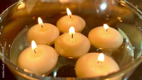 close up of spherical candles floating in glass water bowl for celebratory event