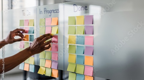 A person organizes tasks on a whiteboard using colorful sticky notes, categorizing them into 