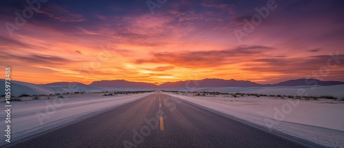 Colorful desert sunset over white sand dunes.