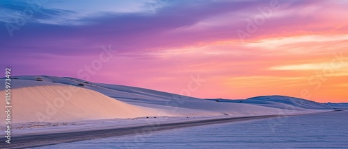 Colorful desert sunset over white sand dunes.
