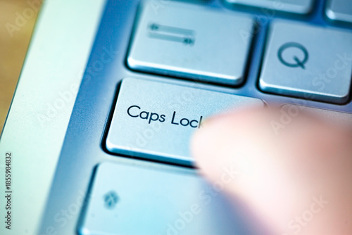 Close-up computer keyboard keys and finger, top view.