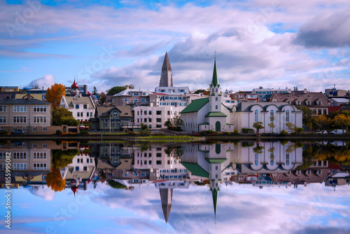 Obraz na plátne Reykjavík City skyline over Lake Tjörnin, with Fríkirkjan in the foreground, traditional houses lining the shore, and Hallgrimskirkja rising behind, a tranquil blend of heritage and modernity