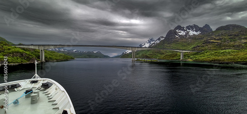 Cruise Ship Approaches High Bridge Over Calm Fjord Near Stokmarknes At The Lofoten In Norway