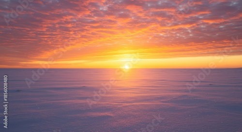 Brilliant orange and yellow sunrise illuminates a vast, snow-covered landscape under textured clouds