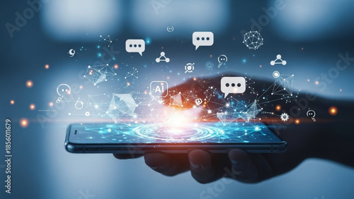 A hand holding a smartphone with glowing blue screen and social media icons floating above it in a dark room with blurred background