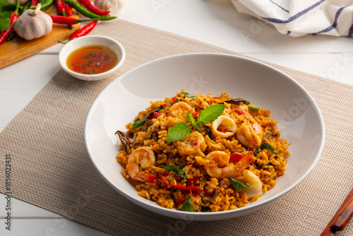 Seafood Tom Yum Fried Rice,Stir fried rice with shrimp and squid with chilli sauce on white plate