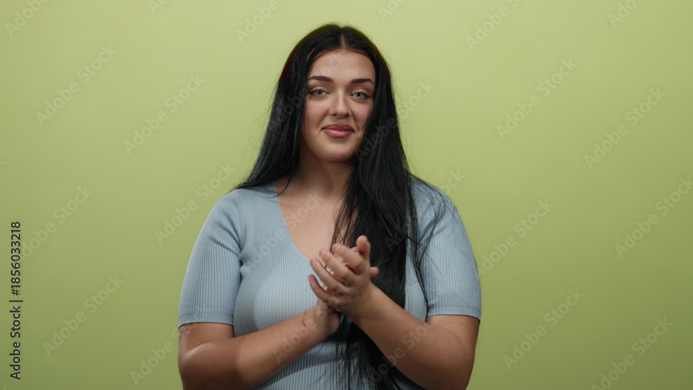 Obraz premium Young plus size woman in blue shirt clapping against isolated yellow wall background.