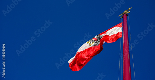 National flag of Austria with coat of arms. Austrian flag on flagpole. Flag of Austria with eagle emblem.