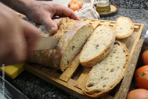 Man cutting a rustic bread with Kalamata Olives made from 2 kilos of flour, homemade