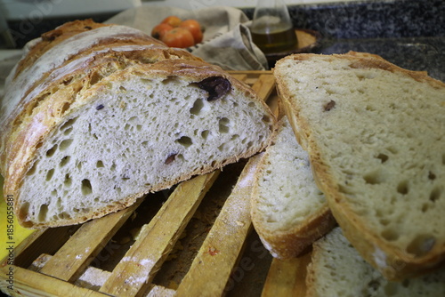 Man cutting a rustic bread with Kalamata Olives made from 2 kilos of flour, homemade