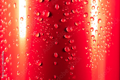 Water droplets on a red aluminum surface with light reflections