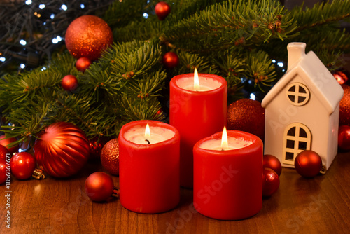 Christmas red candles and fir tree branch on wooden table close-up stock photo images. Three red burning candles and Christmas decorations still life stock photo. Template for background, banner, card