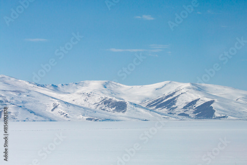 Wide angle sunset over frozen Lake Cildir, Kars, Turkey. Vast snow-covered ice sheet and dramatic sky in winter. Serene cold wilderness of Eastern Anatolia.