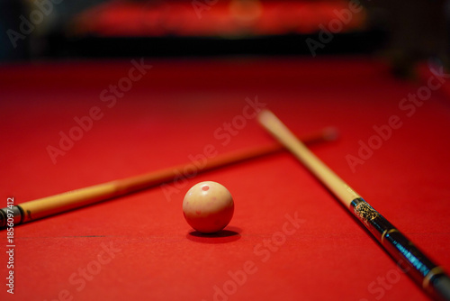 Cue ball centered on a red pool table with crossed billiard cues in the background