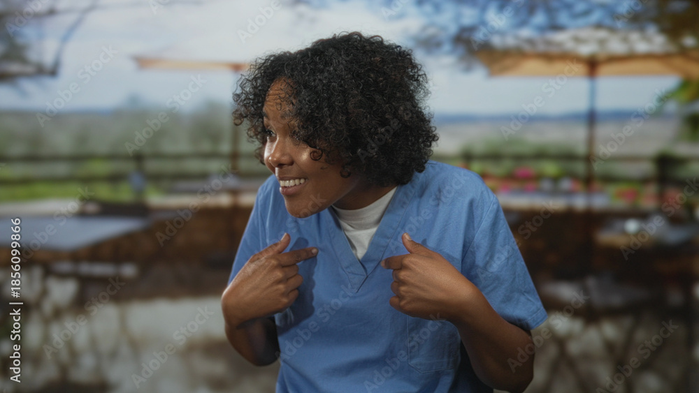 Fototapeta premium Smiling woman pointing her thumbs to her chest on a restaurant terrace overlooking landscape; inner pride.