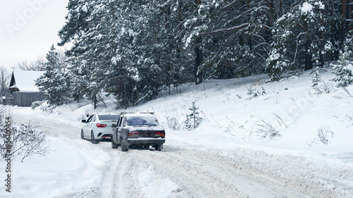 Traffic after a snowfall. A trip out of town. Two cars are spinning in a snow rut on the highway.