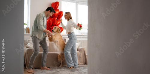 Joyful couple dancing with their dog at home, celebrating love, happiness and family connection.
