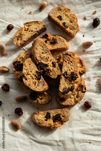Italian cantuccini biscotti with hazelnuts and cranberries served on a white linen cloth with scattered ingredients