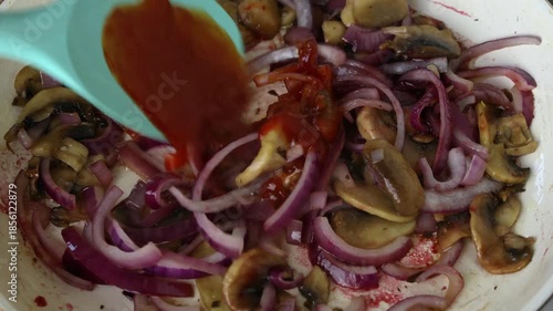 Sauteing sliced mushrooms and red onions with sauce
