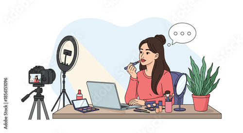 Professional beauty vlogger applying lipstick while recording a makeup tutorial video at her desk with camera, ring light, and laptop.