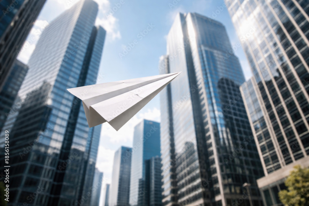 Obraz premium A paper plane against the background of skyscrapers.