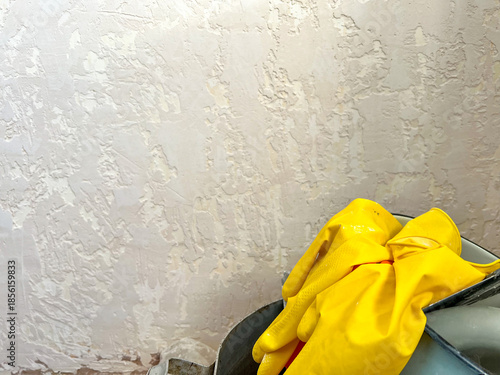 Renovating wall texture with yellow protective gloves