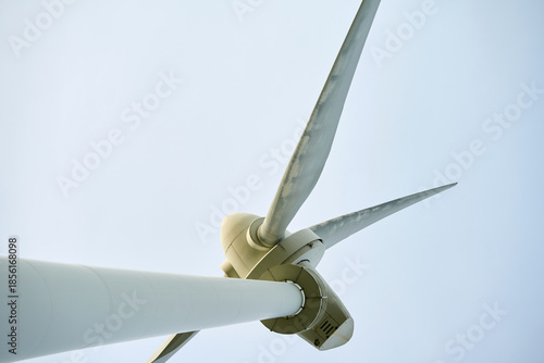 Bild auf Leinwand Close up of wind turbine with three blades against clear sky, viewed from below